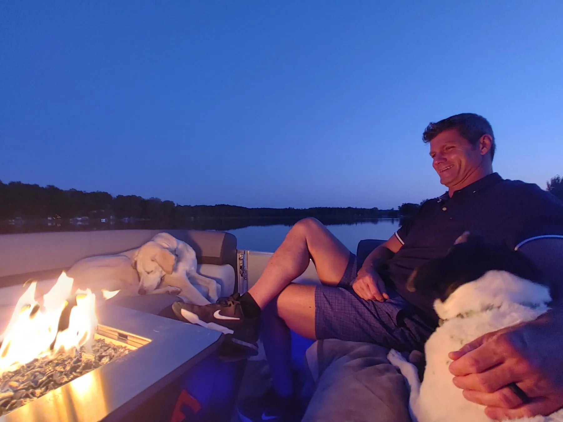 Owner relaxing with his dogs beside the Floating Flame at dusk